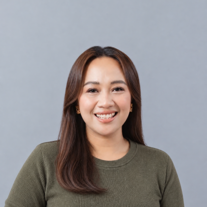 Dr Michelle Martinez smiles at the camera in front of a grey background. She has long dark hair and is wearing a green top.